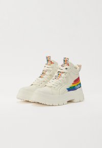 Zapatillas altas blancas con suela gruesa, que presentan detalles de rayas de colores y etiquetas de tirón coloridas. Material de lona suave, diseño con cordones.
