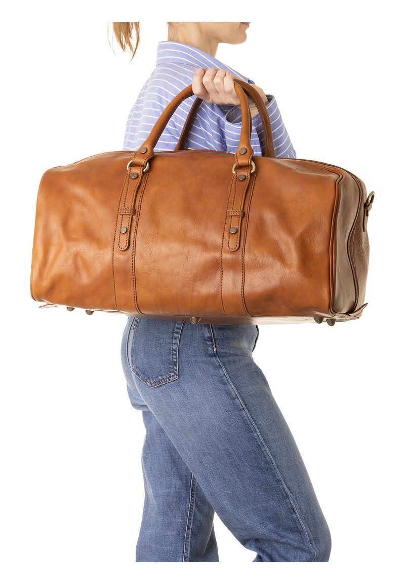 Borsa da viaggio in pelle marrone con manici doppi, due cuciture verticali e accenti in metallo. Presenta quattro piedini protettivi sul fondo.