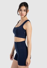 Conjunto de sujetador deportivo azul marino y pantalones cortos de cintura alta, hecho de tela elástica, con tirantes anchos, diseño sin costuras y detalles de costura sutiles.