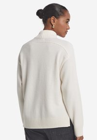 Der cremefarbene Pullover aus Wollmischung verfügt über einen hohen Kragen, einen gerippten Saum und eine lockere Passform. Strukturierter Stoff mit glatter Oberfläche. Einfaches, sauberes Design.