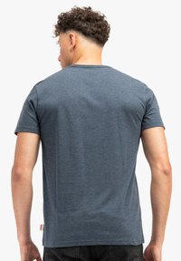 Camiseta de algodón azul oscura, de mangas cortas, con cuello redondo, textura suave, con una pequeña etiqueta de logo en la parte inferior izquierda.
