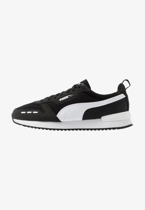 Schwarz-weiße Sportschuhe mit einem Obermaterial aus Mesh, Wildlederakzenten und einer dicken Gummisohle mit strukturiertem Profil und Markenlogo.