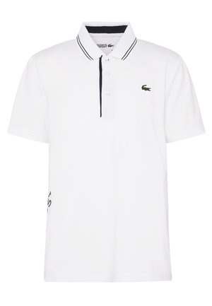 Weißes Poloshirt mit kurzen Ärmeln, marineblauem Besatz am Kragen und an der Knopfleiste, mit einem kleinen grünen Krokodil-Logo auf der linken Brust.