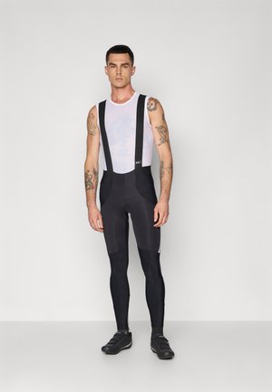 Schwarze Radsport-Trägershorts mit verstellbaren Trägern, einem oberen Netzmaterial und gepolstertem Sitzbereich. Merkmale sind glättender Stoff und strapazierfähige Nähte.