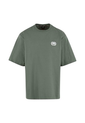 Camiseta de algodón verde con mangas cortas, cuello redondo y un pequeño logo blanco en el lado izquierdo del pecho. Textura suave, ajuste relajado.