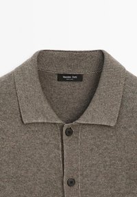 Grå kortärmad polotröja med ribbad krage, försedd med tre svarta knappar och en sydd etikett som läser "Massimo Dutti."
