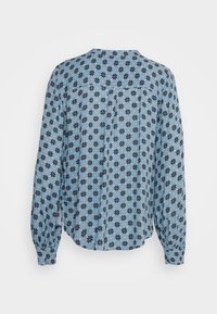 Blouse longue bleue à manches longues avec un motif floral noir, poignets boutonnés et un détail de pli au dos. Tissu doux avec une coupe décontractée.