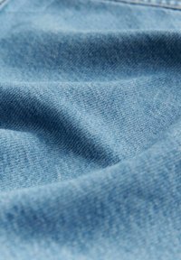 Heledsinise Denim kangas lähedalt vaadates, näidates sujuvat tekstuuri peene kudumise mustriga ja pehme, paindliku langenemisega.