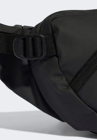 Black fabric waist bag with a textured finish, featuring a webbed strap and an adjustable buckle. Compact design with a minimalistic look.