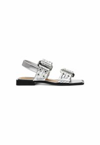 Silberne, metallische Sandalen mit zwei breiten Riemen, geflochtenen Akzenten und Druckknopf-Beschlägen, ausgestattet mit einer flachen schwarzen Sohle und offenem Fersen-Design.