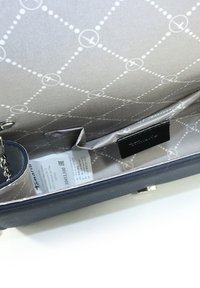 Sac à main bleu marine avec un extérieur lisse et texturé. L'intérieur est doublé de gris clair avec des motifs géométriques et plusieurs emplacements pour cartes.