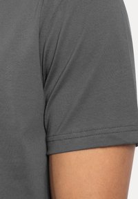 Graues Kurzarmshirt mit weicher Textur, das einen runden Halsausschnitt und verstärkte Nähte am Ärmelrand und an der Schulter aufweist.