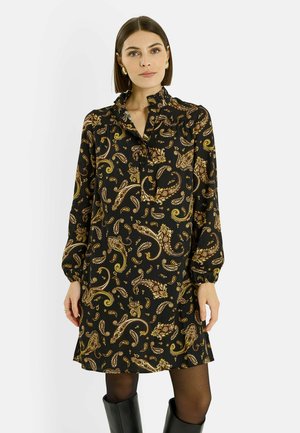 Vestido negro de manga larga con patrón de cachemira dorado, tela suave, cuello fruncido y tapeta de botones. Combinado con botas negras hasta la rodilla.