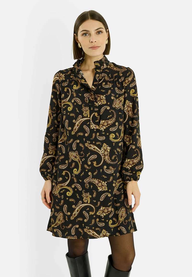 Vestido negro de manga larga con patrón de cachemira dorado, tela suave, cuello fruncido y tapeta de botones. Combinado con botas negras hasta la rodilla.