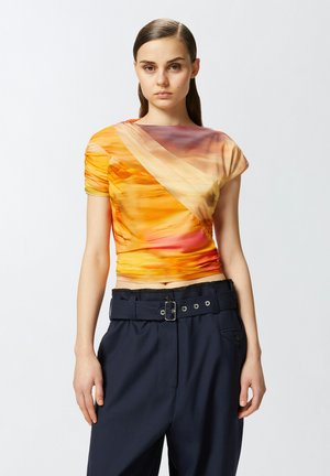 Top aderente con motivi astratti arancioni e gialli, maniche corte e design drappeggiato, abbinato a pantaloni navy a vita alta e una cintura con fibbia.