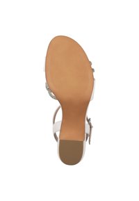 Talons blancs avec un dessus lisse, une sangle ajustable au niveau de la cheville et une semelle en caoutchouc texturée. Présente des accents décoratifs sur le côté. Taille 37.