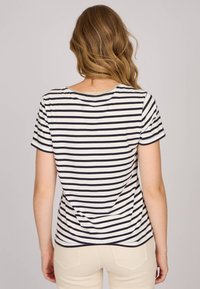 T-shirt à rayures courtes en crème et bleu marine, avec un col rond et un accent doré. Manches courtes et coupe décontractée.