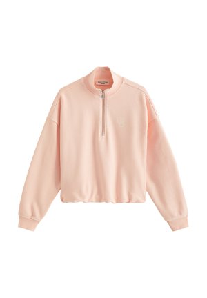 Sweat-shirt court rose clair avec manches longues, poignets côtelés, fermeture éclair sur le devant et logo brodé discret sur la poitrine.