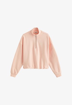 Sweat-shirt court rose clair avec manches longues, poignets côtelés, fermeture éclair sur le devant et logo brodé discret sur la poitrine.