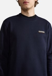 Felpa blu navy in cotone con scollo a girocollo a coste. Presenta una piccola toppa rettangolare con logo sulla parte sinistra del petto.