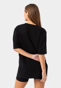 Svart bomulls t-shirt med korta ärmar, avslappnad passform, rund halsringning och en jämn yta. Baksidan är enkel utan synliga logotyper.