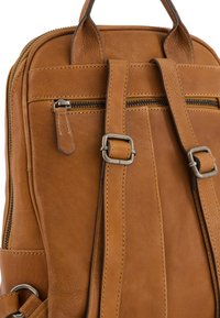 Brown leather backpack featuring two adjustable straps, a top handle, and silver-tone hardware with visible stitching details.