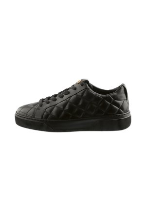 Sort lavt sneakers med quiltet læderoverdel, sorte snørebånd og tyk tekstureret gummisål, vist i sideprofil.