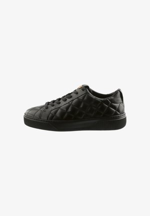 Sort lavt sneakers med quiltet læderoverdel, sorte snørebånd og tyk tekstureret gummisål, vist i sideprofil.