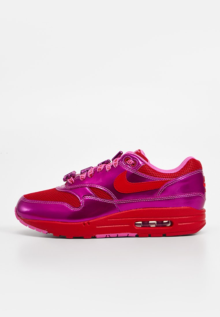 Baskets Nike Air Max en rouge vif et rose. Elles présentent une tige en mesh, un bout arrondi et une unité d9amortissement visible dans la semelle.