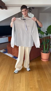 Beige színű, hosszú ujjú póló kerek nyakkivágással, puha tapintással és látható címkével, egy személyen, aki krémszínű nadrágot visel.