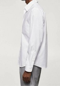 Chemise blanche à manches longues en coton, avec un col classique, des poignets à boutons, une coupe droite et une texture lisse.