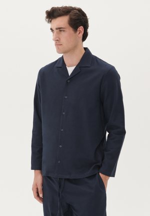 Marineblaues Langarmshirt mit lockerer Passform, offenem Kragen und vorderem Knopfverschluss. Weicher Stoff mit glatter Textur und minimalistischem Design.