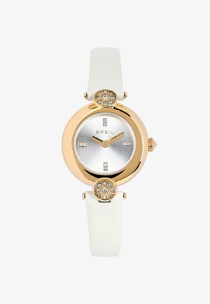 Montre ronde en or avec bracelet blanc, accents en cristal sur la lunette et le cadran, aiguilles dorées affichant 10:10, nom de la marque Breil sur le cadran argenté.