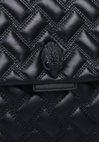 Czarna torebka z pikowanej skóry, wyróżniająca się teksturowaną powierzchnią, charakterystycznym zapięciem z czarnego metalu z ozdobami oraz płaską klapką zamykającą.