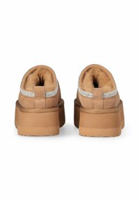 Scarpe slip-on in suede marrone con un interno morbido, dotate di un accento scintillante di strass lungo il colletto e di una suola spessa e testurizzata.
