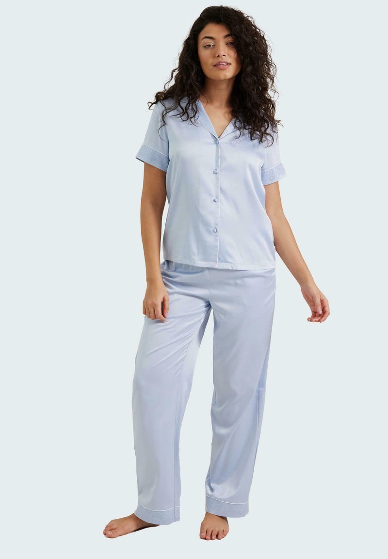 Conjunto de pijama de satén azul claro que incluye una camisa de botones de mangas cortas y pantalones a juego con dobladillos ajustados y un corte relajado.