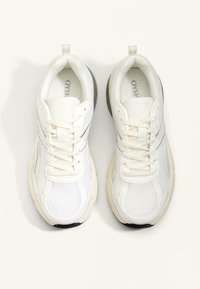 Bijele atletske tenisice s mrežastom gornjom površinom, okruglim vrhom, podstavljenim ovratnikom i teksturiranom potplatom s suptilnim sivim akcentom.