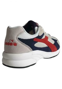 Sneaker con un mix di materiali in suede e mesh beige, blu navy e rosso. Presenta una suola bianca spessa e un logo prominente rosso sul tallone.