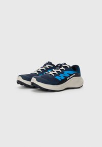 Baskets de course bleu marine avec un dessus texturé, des accents bleu vif, des lacets blancs et une semelle épaisse couleur crème pour l'adhérence.