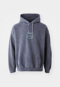 Felpa navy in tessuto morbido con tasca frontale. Presenta un design circolare con il testo “La Vita è Un Cerchio” in colori verde e blu.