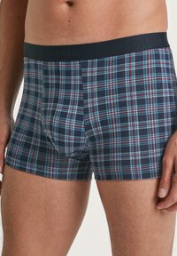 Bermudashorts aus dehnbarem Stoff, mit einem navyblauen Karomuster, das rote und hellblaue Linien enthält. Weicher Bund mit dem Aufdruck "CALIDA".