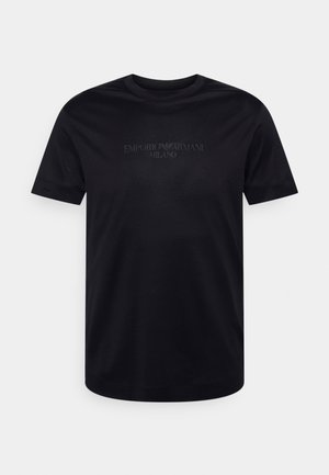 Camiseta negra de algodón con mangas cortas, cuello redondo y logo en relieve "EMPORIO ARMANI MILANO" centrado en el pecho. Textura lisa.