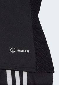 Tejido atlético negro con un panel texturizado, acentuado con el logotipo "AEROREADY" en blanco y tres franjas verticales.