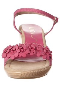Pink suede sandal with floral embellishments, open toe design, ankle strap, and cushioned insole with a wooden-style wedge heel.
