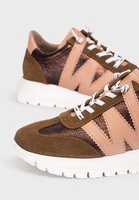 Brązowe i różowe skórzane sneakersy z białymi sznurówkami i grubymi białymi podeszwami, z zygzakowatym wzorem po bokach.