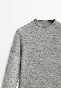 Harmaa pitkähihainen neulepusero, jossa on pyöreä pääntie, raglan-hihat ja pehmeä, teksturoitu materiaali. Yksinkertainen, koristamaton muotoilu, jossa on sileä pinta.