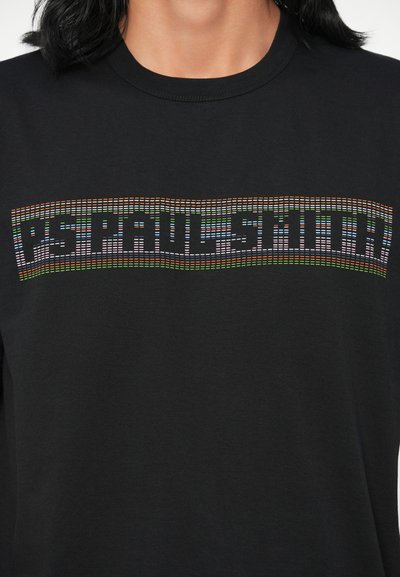 Musta crewneck-huppari, jossa on värikäs pikselöity "PS PAUL SMITH" -logo rinnassa vaihtelevissa väreissä ja kuvioissa. Pehmeä rakenne.
