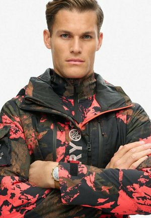 Men's jacket with a camouflage pattern in black, red, and brown. Features a high collar, zippers, and wrist adjustments. Accented with branded logo.