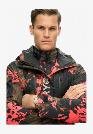 Męska kurtka w kamuflażowym wzorze w czerni, czerwieni i brązie. Posiada wysoki kołnierz, zamki błyskawiczne oraz regulację w okolicach nadgarstków. Akcentowana markowym logo.