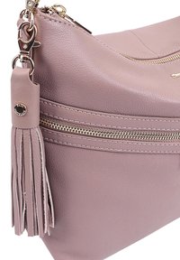 Lichtroze leren schoudertas met een textuurafwerking, een gouden ritssluiting en decoratieve franjes aan de zijkant.